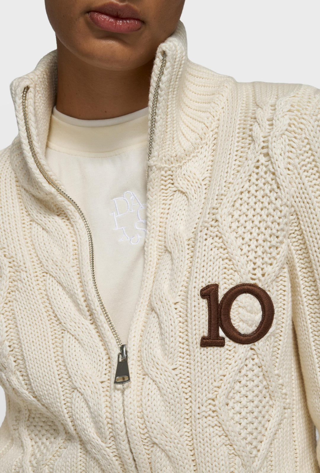 Kremowy sweter zapinany na zamek z warkoczowym splotem i logo 10