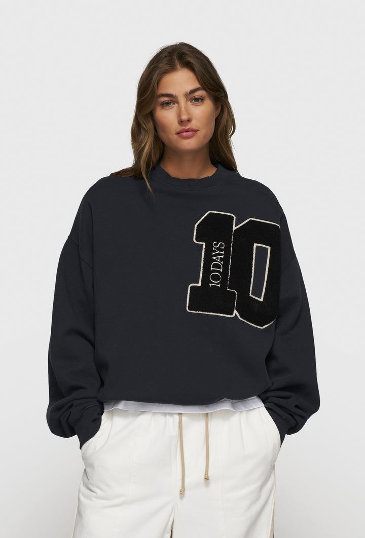 Nierozpinana bluza w granatowym kolorze z widoczną aplikacją z logo marki