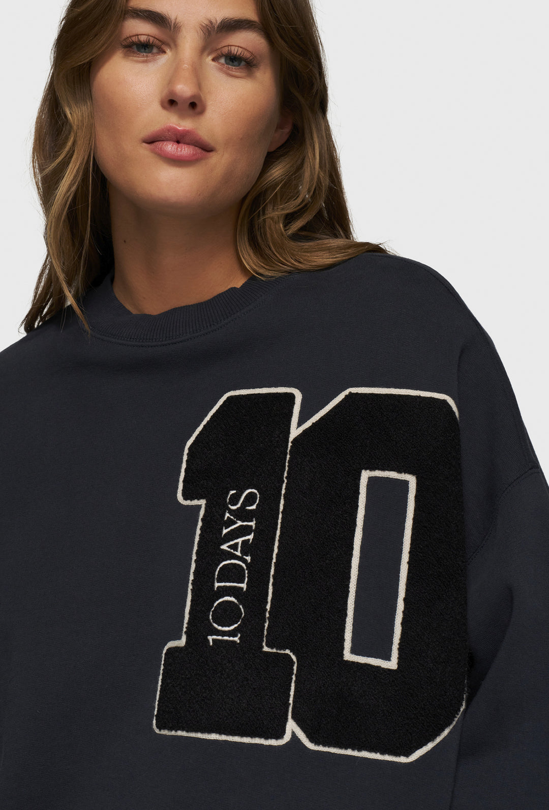 Nierozpinana bluza w granatowym kolorze z widoczną aplikacją z logo marki